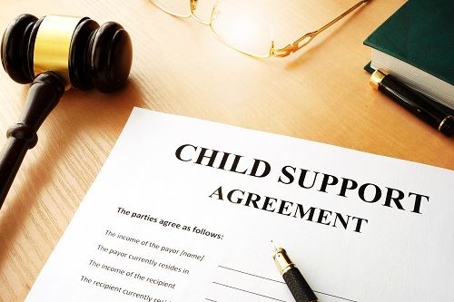 Child support agreement with pens, a gavel, glasses, and a book.
